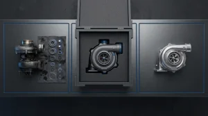 Overhead view of three bench zones: a worn turbocharger with new bearings and seals, a reconditioned turbo in a foam-lined crate, and an unused turbo